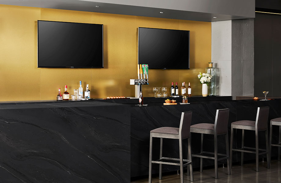 5015-11 Black Painted Marble bar top with M6423 Brushed Brass laminate accent wall panels, TVs and chairs